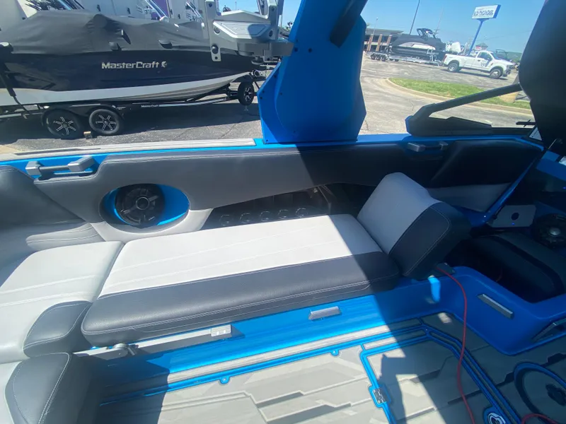 Slide: The Image of 2021 Supra SL 450 boat interior with blue and gray seating, parked outdoors. - 28