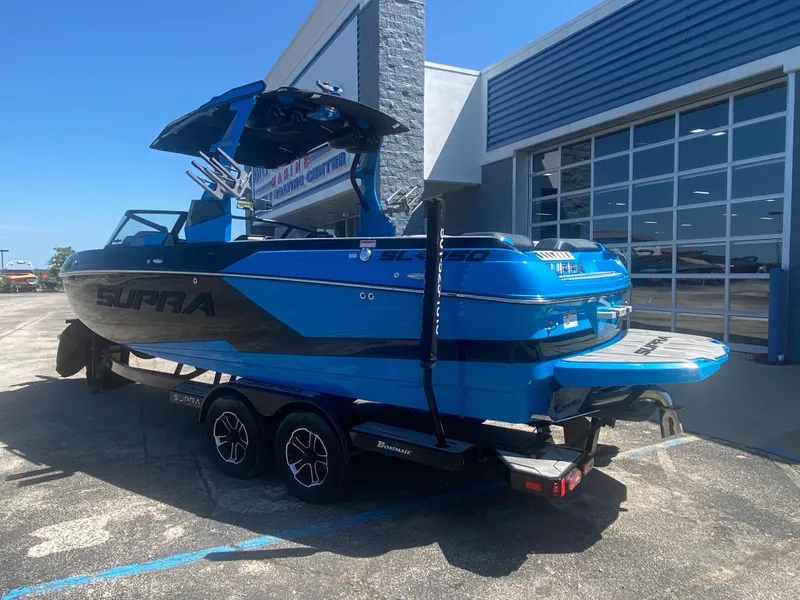 Slide: The Image of 2021 Supra SL 450 boat in blue, parked on a trailer outside a building. - 3