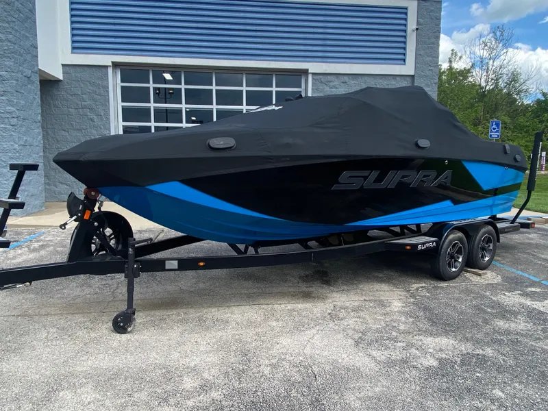 Slide: The Image of 2021 Supra SL 450 boat with cover, parked on a trailer outside a building. - 38