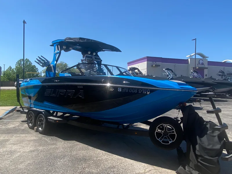 Slide: The Image of 2021 Supra SL 450 boat in vibrant blue, parked on a trailer under clear skies. - 7
