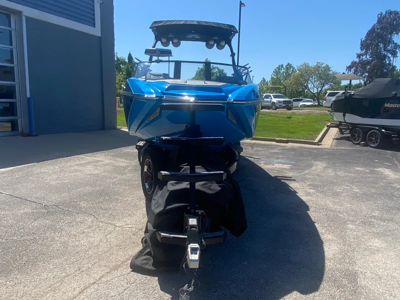 Slide: The Image of 2021 Supra SL 450 boat in blue, parked outdoors on a sunny day. - 8