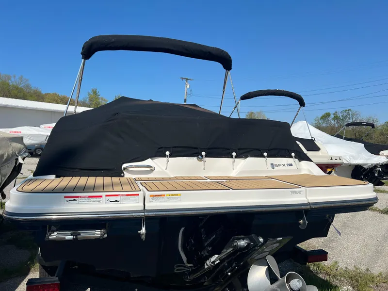 Slide: The Image of 2020 Sea Ray SPX 230 boat with black cover and wooden deck, parked outdoors. - 4
