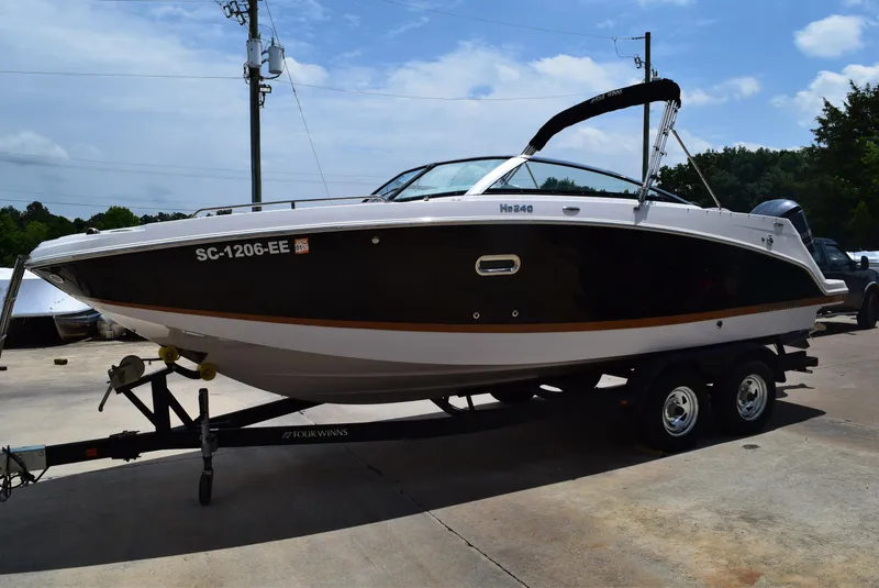 Slide: The Image of 2018 Four Winns HD240 OB boat on trailer, black and white design, parked outdoors. - 1
