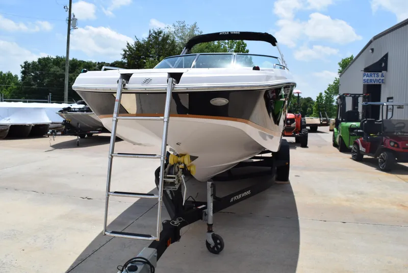 Slide: The Image of 2018 Four Winns HD240 OB boat on trailer, parked outdoors near service area. - 2