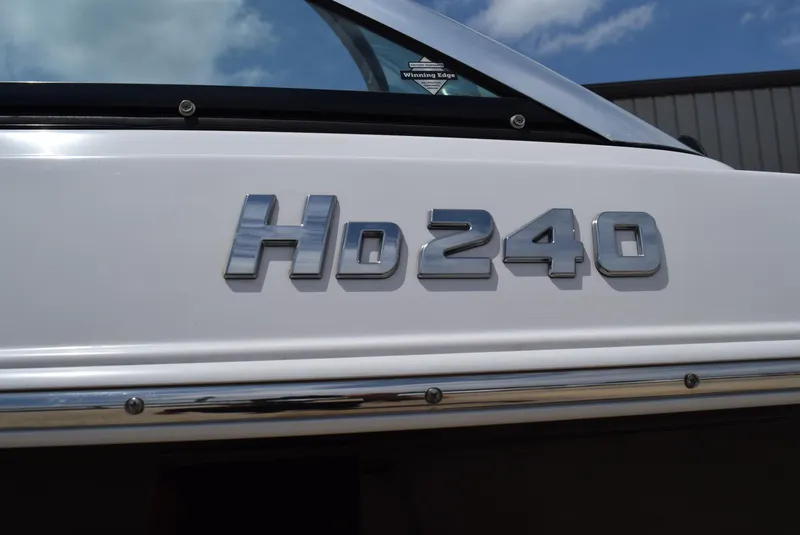 Slide: The Image of 2018 Four Winns HD240 OB boat emblem on white exterior under blue sky. - 5