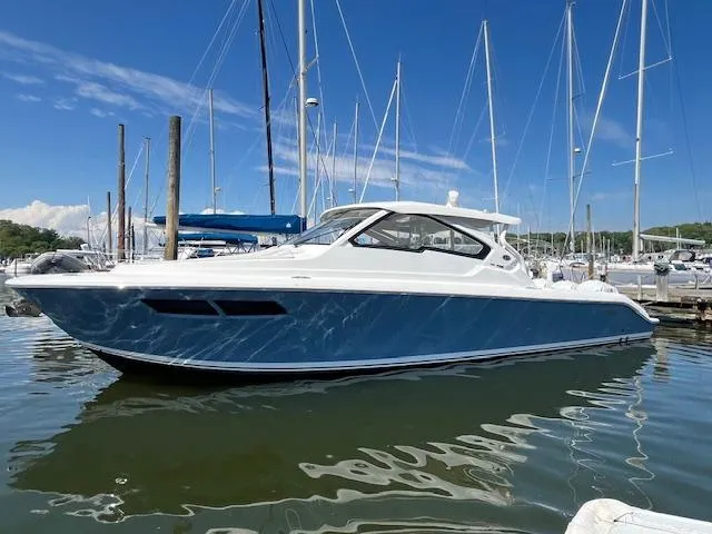 The Image of 2019 Pursuit DC 365 Dual Console boat docked in marina under clear blue sky. - 0