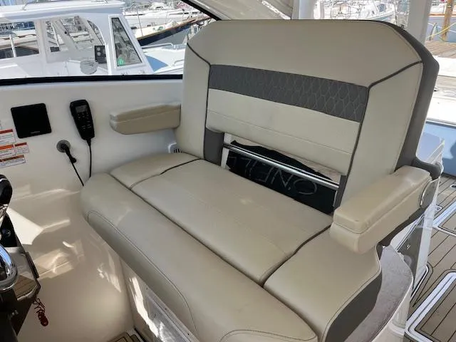Slide: The Image of 2019 Pursuit DC 365 Dual Console boat interior with beige seating and armrests. - 23