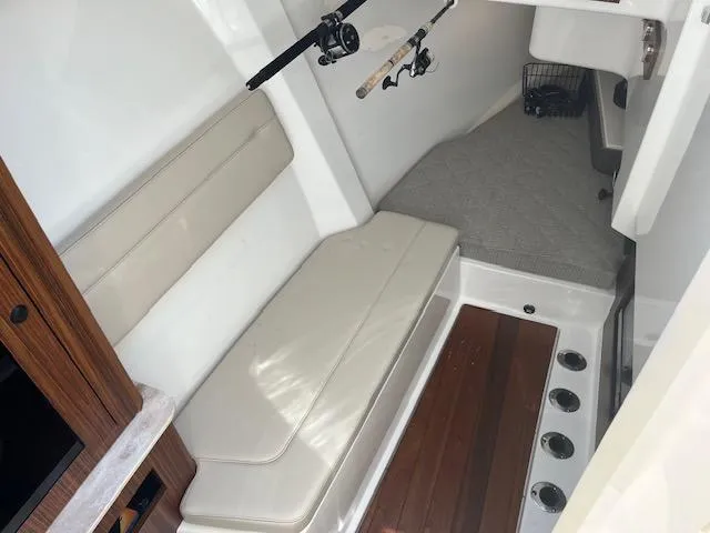 Slide: The Image of 2019 Pursuit DC 365 Dual Console interior with seating, fishing rods, and wooden flooring. - 29