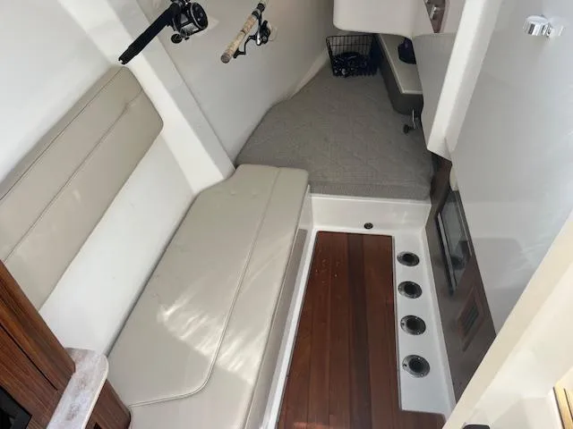 Slide: The Image of 2019 Pursuit DC 365 Dual Console interior with seating, fishing rods, and wooden flooring. - 30