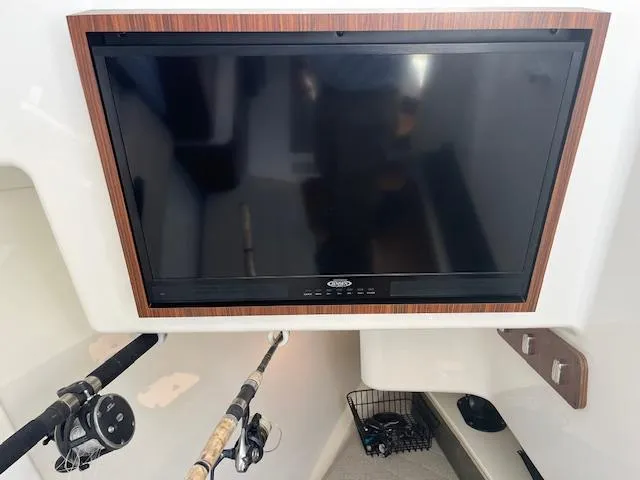 Slide: The Image of 2019 Pursuit DC 365 Dual Console interior with mounted TV and fishing rods. - 33