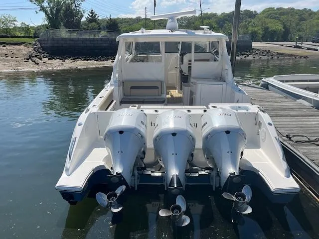 Slide: The Image of 2019 Pursuit DC 365 Dual Console boat with triple outboard engines docked at a marina. - 8