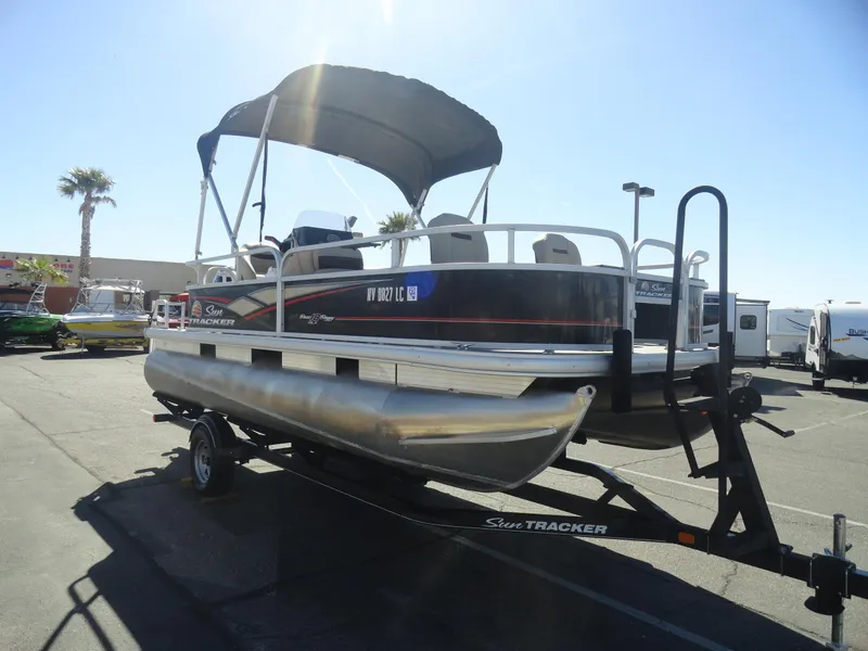 Slide: The Image of 2019 Sun Tracker Bass Buggy 18 DLX pontoon boat on trailer, parked outdoors. - 5