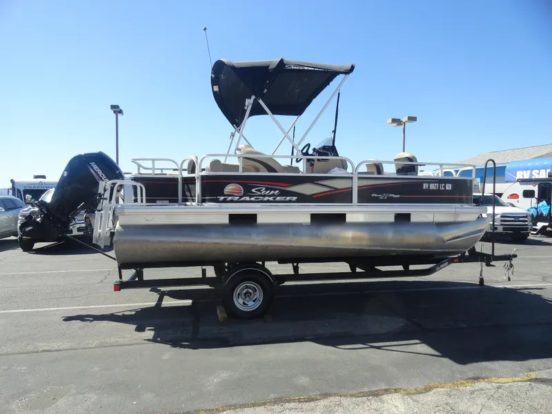 Slide: The Image of 2019 Sun Tracker Bass Buggy 18 DLX pontoon boat on trailer, parked outdoors. - 6