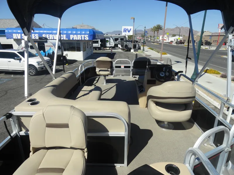 Slide: The Image of 2019 Sun Tracker Bass Buggy 18 DLX pontoon boat with beige seating, parked near RV sales. - 7