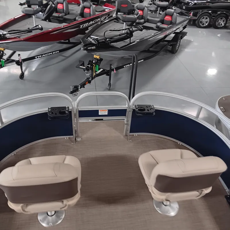 Slide: The Image of 2025 Sun Tracker Bass Buggy 16 XL Select pontoon boat interior with seating and nearby trailers. - 4