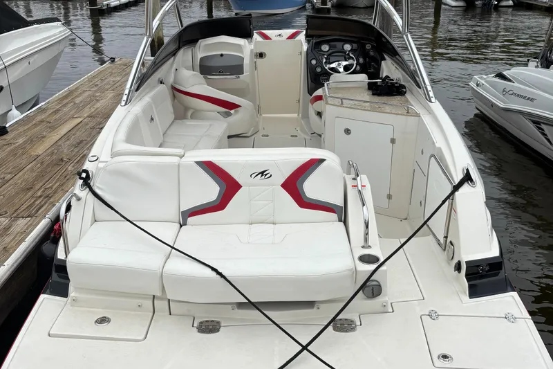 Slide: The Image of 2012 Monterey M5 MSX Sport Boat interior with white seating, docked by waterfront. - 7