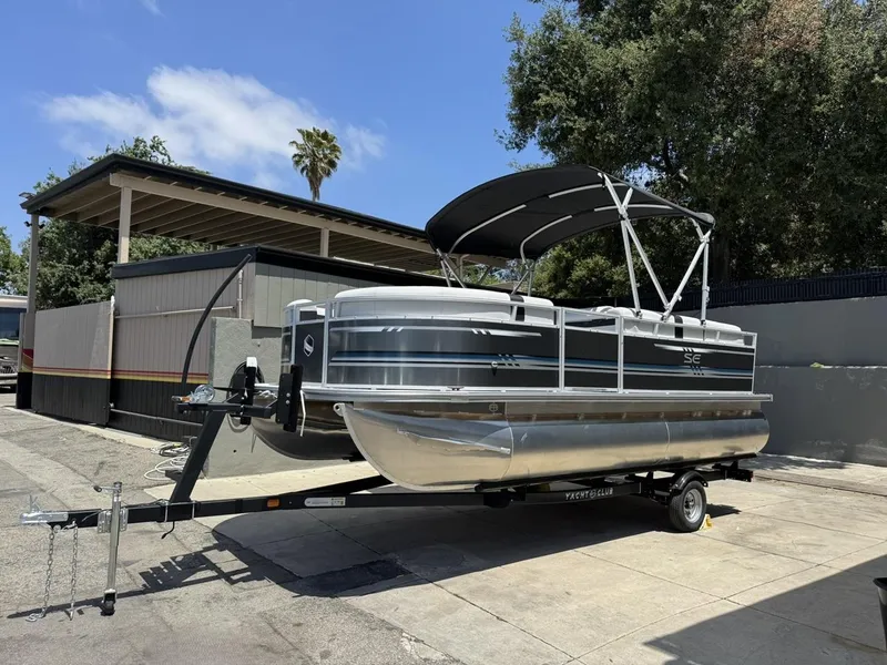 Slide: The Image of 2025 South Bay 18CR SE S Cruise pontoon boat on trailer, parked outdoors. - 1