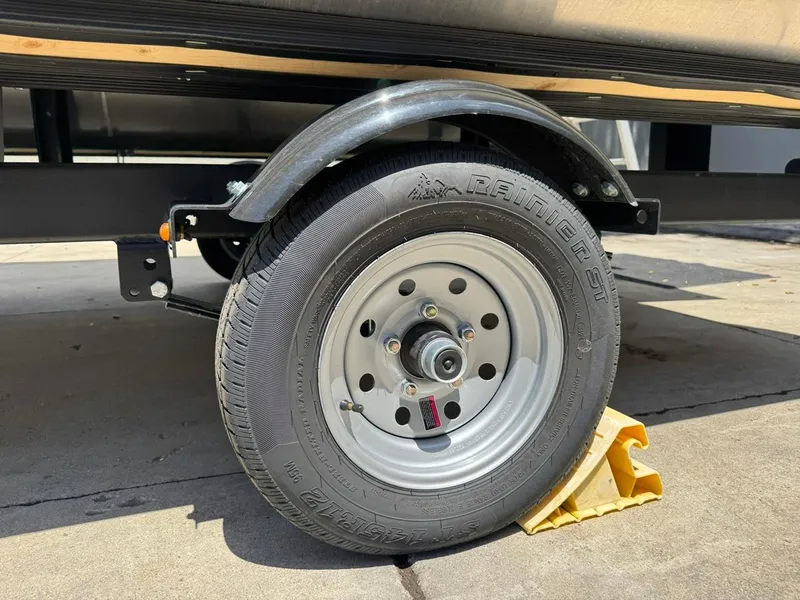 Slide: The Image of Trailer wheel of 2025 South Bay 18CR SE S Cruise, secured with a yellow wheel chock. - 25