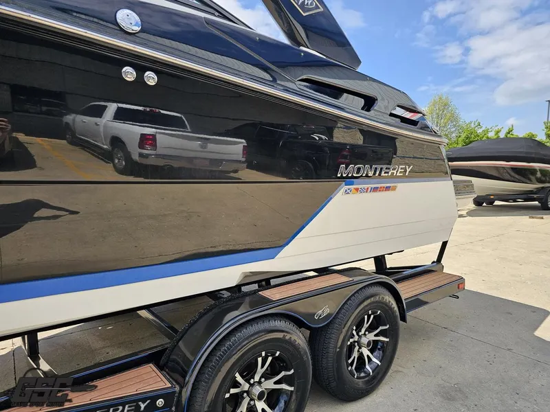 Slide: The Image of 2018 Monterey 258 Super Sport boat on trailer, black and white design, parked outdoors. - 18