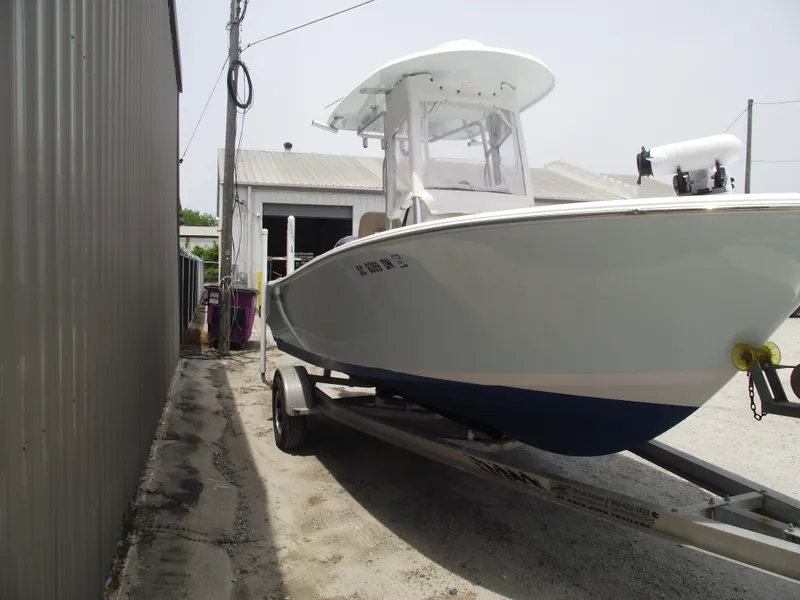 Slide: The Image of 2021 Sportsman Open 212 Center Console boat on trailer near a building. - 2