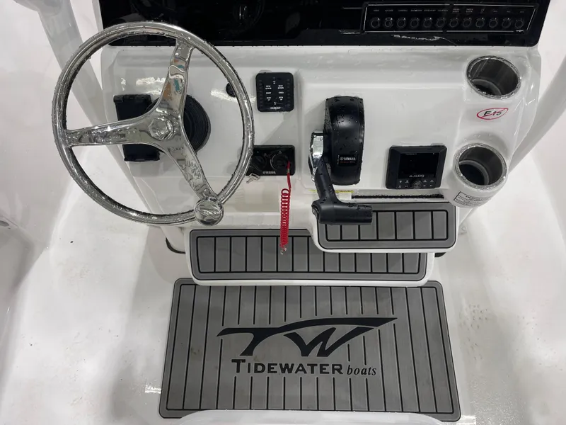 Slide: The Image of 2025 Tidewater 210LXF boat console with steering wheel, controls, and branded mat. - 19
