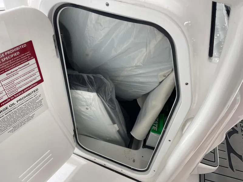Slide: The Image of Storage compartment of 2025 Tidewater 210LXF boat, showing interior contents and safety label. - 27