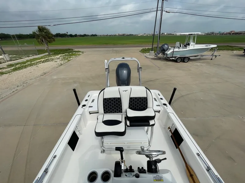 Slide: The Image of 2022 Tidewater 2110BM boat interior with seating and steering wheel, parked on concrete. - 19