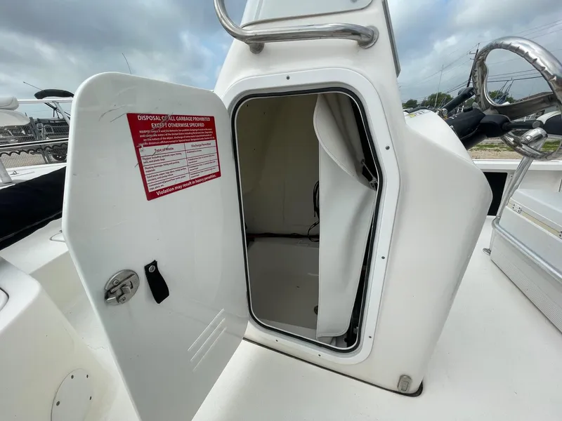 Slide: The Image of 2022 Tidewater 2110BM boat console with open storage compartment and visible warning label. - 28