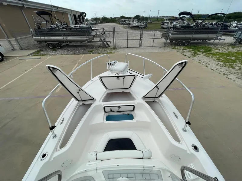 Slide: The Image of 2022 Tidewater 2110BM boat with open storage compartments, docked near other boats. - 30