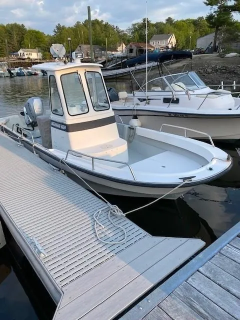 Slide: The Image of 2000 Maritime Skiff 2090 docked at a marina, surrounded by calm water and other boats. - 2