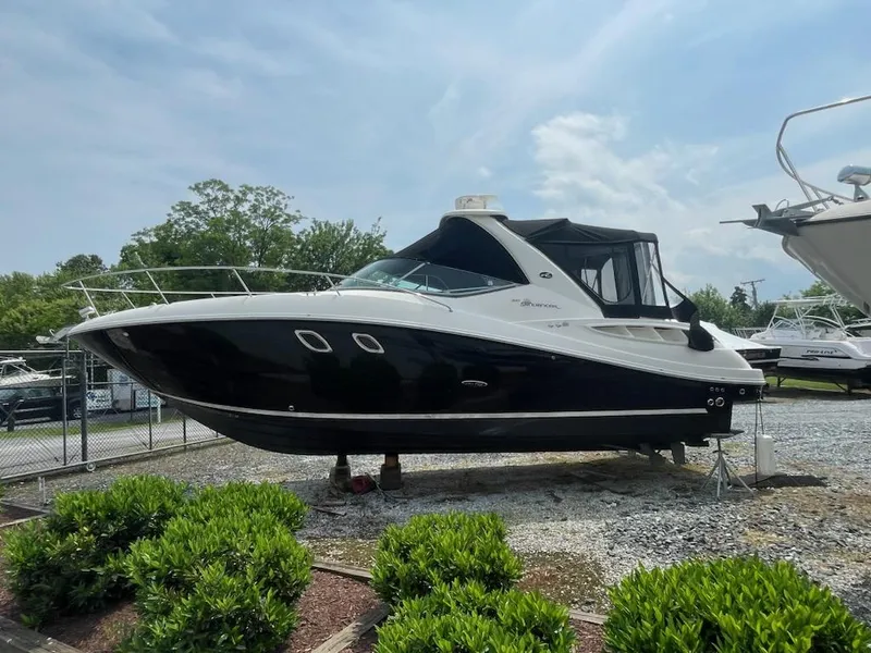 Slide: The Image of 2007 Sea Ray 310 Sundancer boat on display, black and white exterior, parked on gravel. - 2