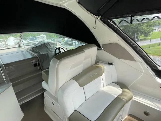 Slide: The Image of 2007 Sea Ray 310 Sundancer interior with white and beige seating, covered helm, and outdoor view. - 21