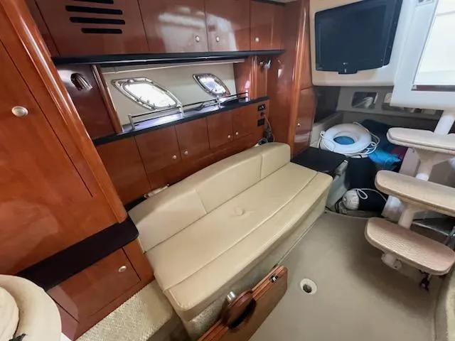 Slide: The Image of 2007 Sea Ray 310 Sundancer interior with beige seating, wooden cabinets, and a mounted TV. - 34