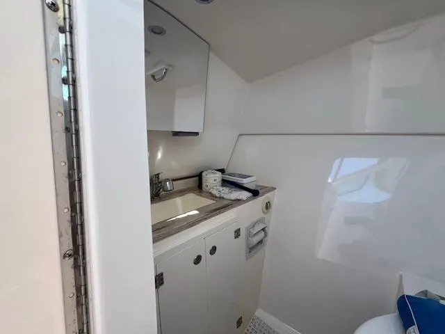 Slide: The Image of 2017 Pursuit DC 325 Dual Console boat bathroom with sink and storage cabinets. - 13