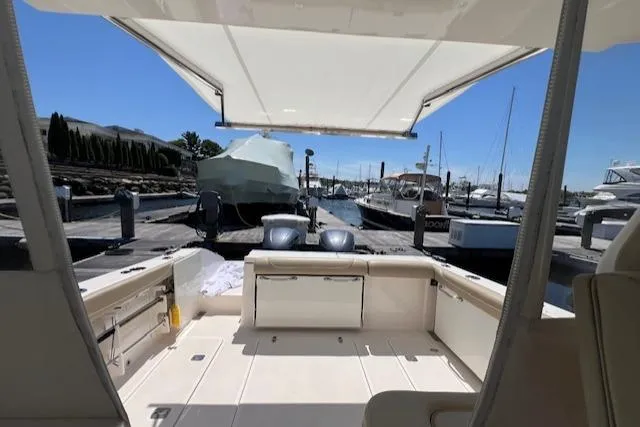 Slide: The Image of 2017 Pursuit DC 325 Dual Console boat docked at marina, featuring spacious deck and canopy. - 17