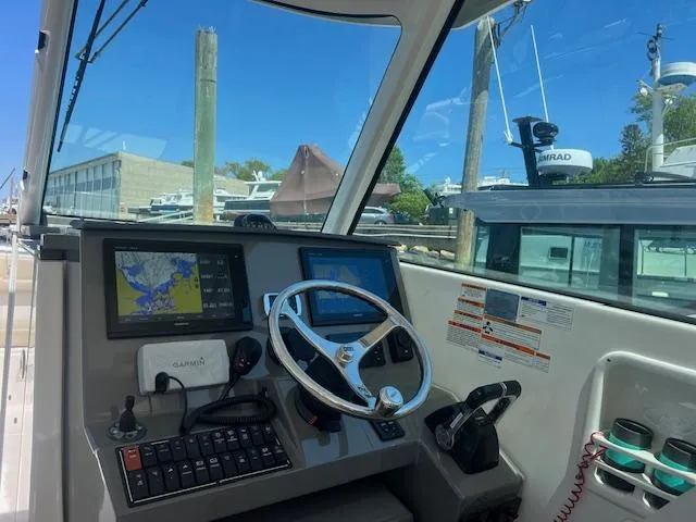Slide: The Image of 2017 Pursuit DC 325 Dual Console boat cockpit with navigation screens and steering wheel. - 20