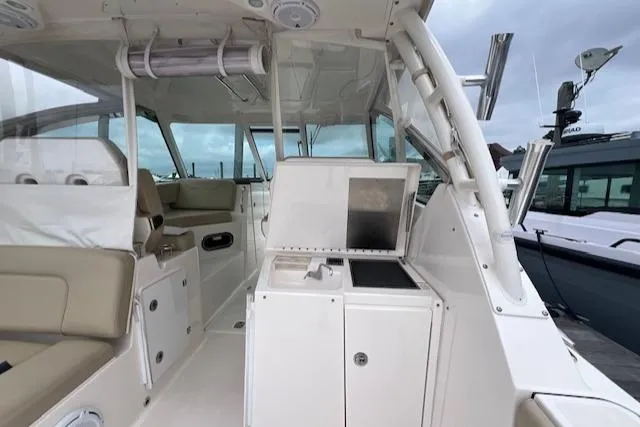 Slide: The Image of 2017 Pursuit DC 325 Dual Console interior with seating and console, docked under cloudy skies. - 22