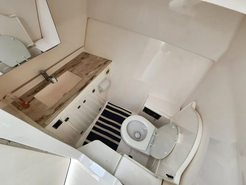 Slide: The Image of 2017 Pursuit DC 325 Dual Console boat bathroom with sink, toilet, and striped rug. - 5