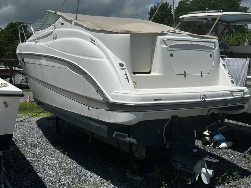 Slide: The Image of 2000 Maxum 2800 SCR boat stern view on gravel, showcasing outdrive and hull details. - 4