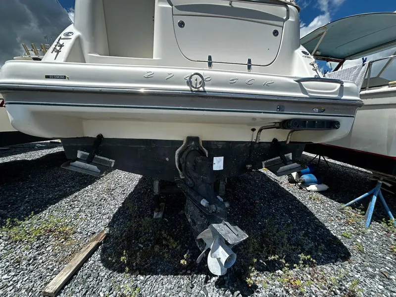 Slide: The Image of 2000 Maxum 2800 SCR boat stern view on gravel, showcasing outdrive and hull details. - 6