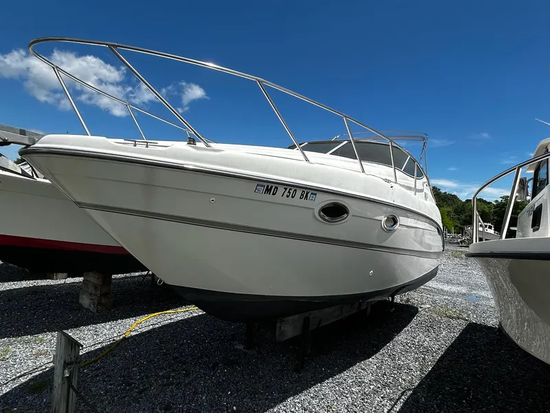 Slide: The Image of 2000 Maxum 2800 SCR boat on gravel lot under clear blue sky. - 8