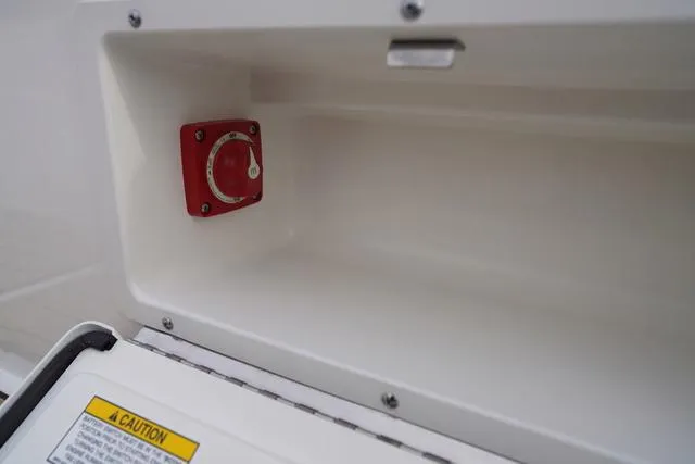 Slide: The Image of 2024 Sea Ray SPX 230 boat compartment with red control knob and caution label. - 39
