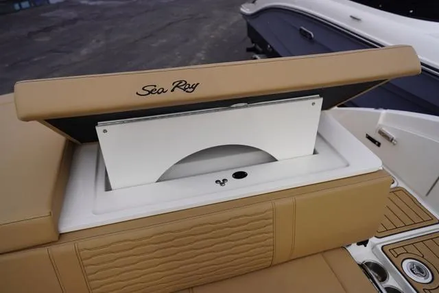 Slide: The Image of 2024 Sea Ray SPX 230 boat storage compartment with tan upholstery and open lid. - 44