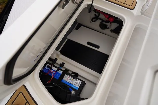 Slide: The Image of 2024 Sea Ray SPX 230 boat storage compartment with battery and equipment. - 49