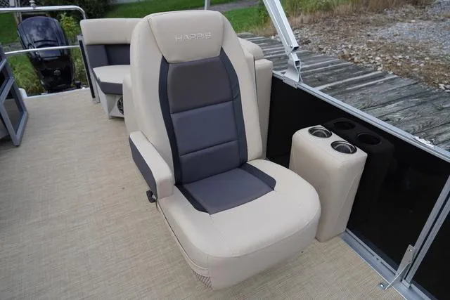 Slide: The Image of 2024 Harris Cruiser 230 CWDH boat interior with beige and gray seating, cup holders, and deck view. - 25