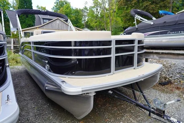 Slide: The Image of 2024 Harris Cruiser 230 CWDH pontoon boat on a trailer, parked outdoors. - 6