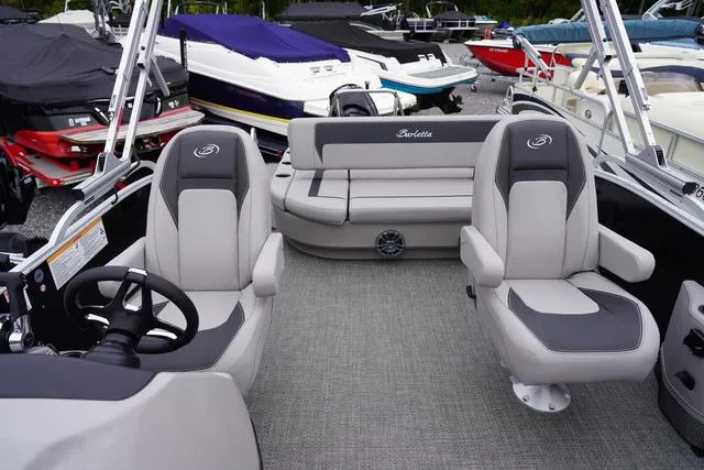 Slide: The Image of 2025 Barletta Boats A22UC interior with gray seating and steering wheel, docked among other boats. - 34