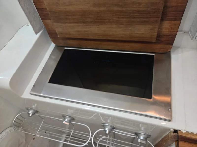 Slide: The Image of 1989 Chris-Craft 42 Sportfish Commander kitchen stove with wooden cover and metal knobs. - 11