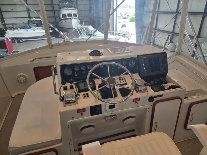 Slide: The Image of 1989 Chris-Craft 42 Sportfish Commander helm with controls and navigation equipment in a marina setting. - 16