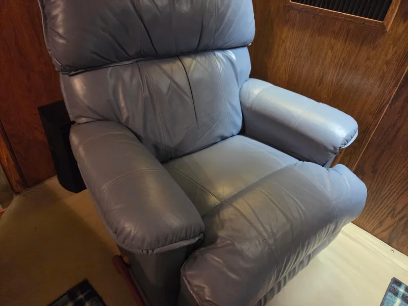 Slide: The Image of A comfortable blue leather recliner chair in a cozy room setting. - 36